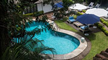 Una piscina al aire libre, sombrillas, sillones reclinables de piscina