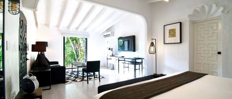 A modern hotel room with a large bed, a desk, and a seating area with a view of the outdoors.