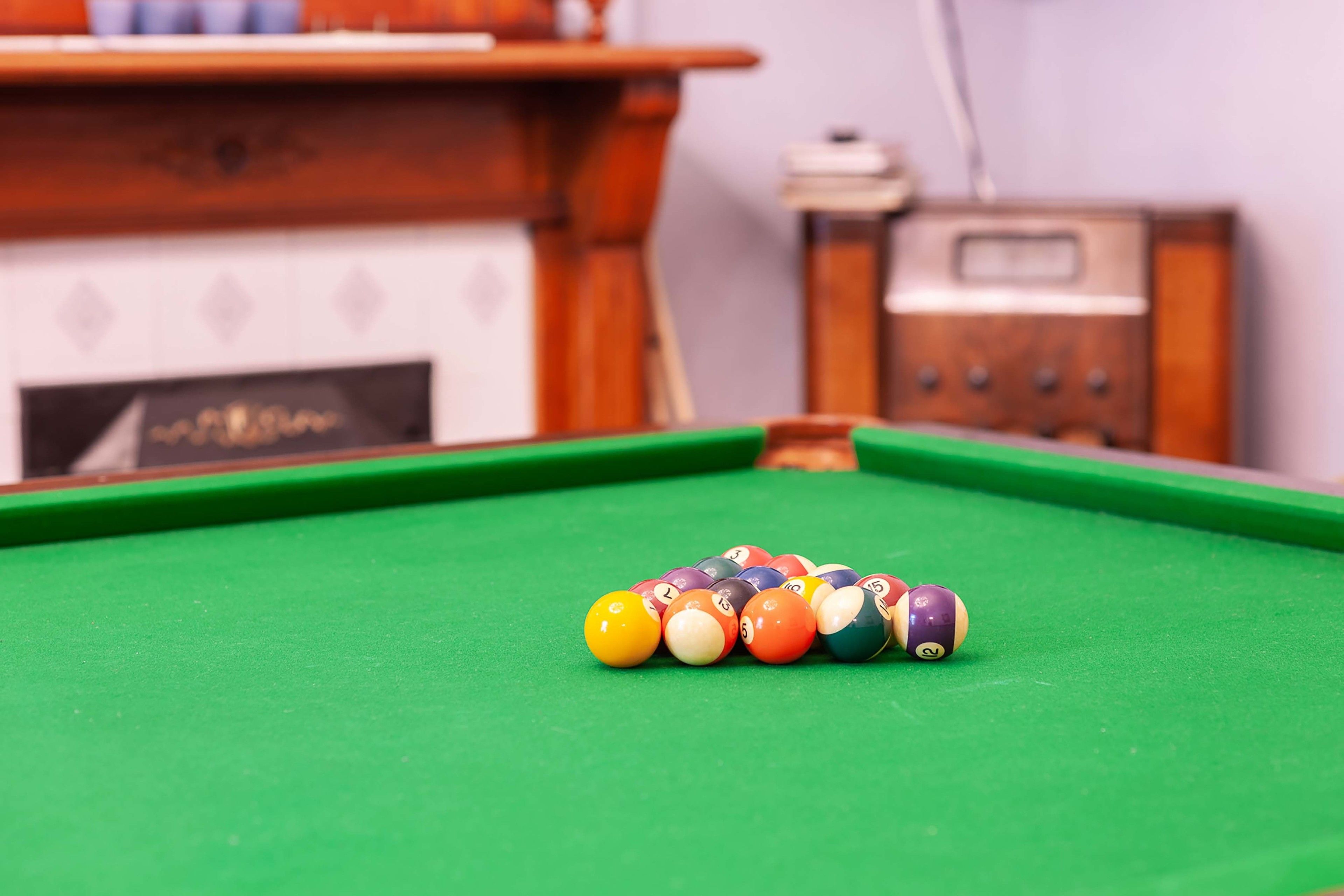 A pool table with a set of billiard balls arranged in a triangle formation.