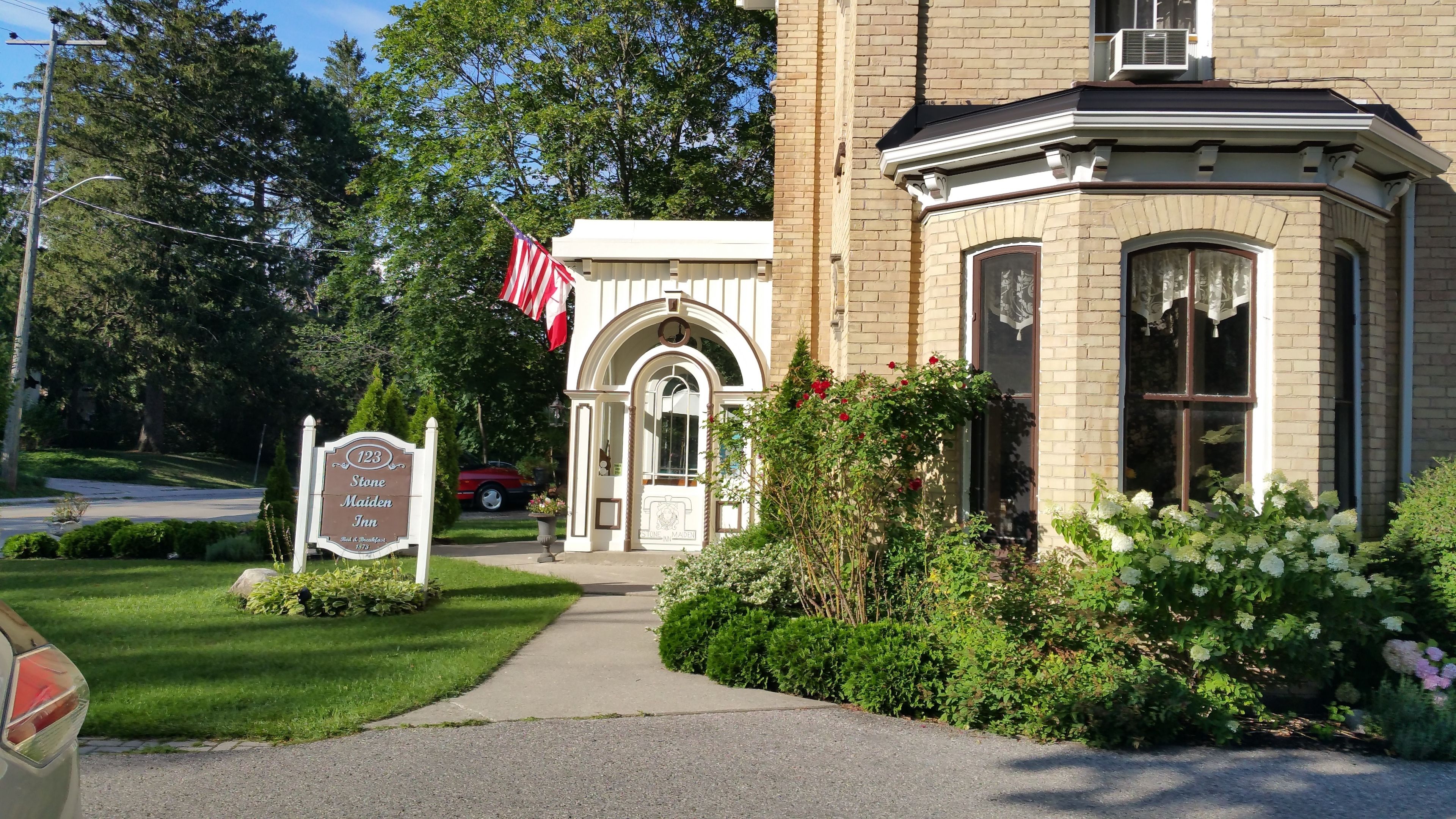 A Stone Maiden Inn with a brick facade, a welcoming entrance, and a well-maintained garden.