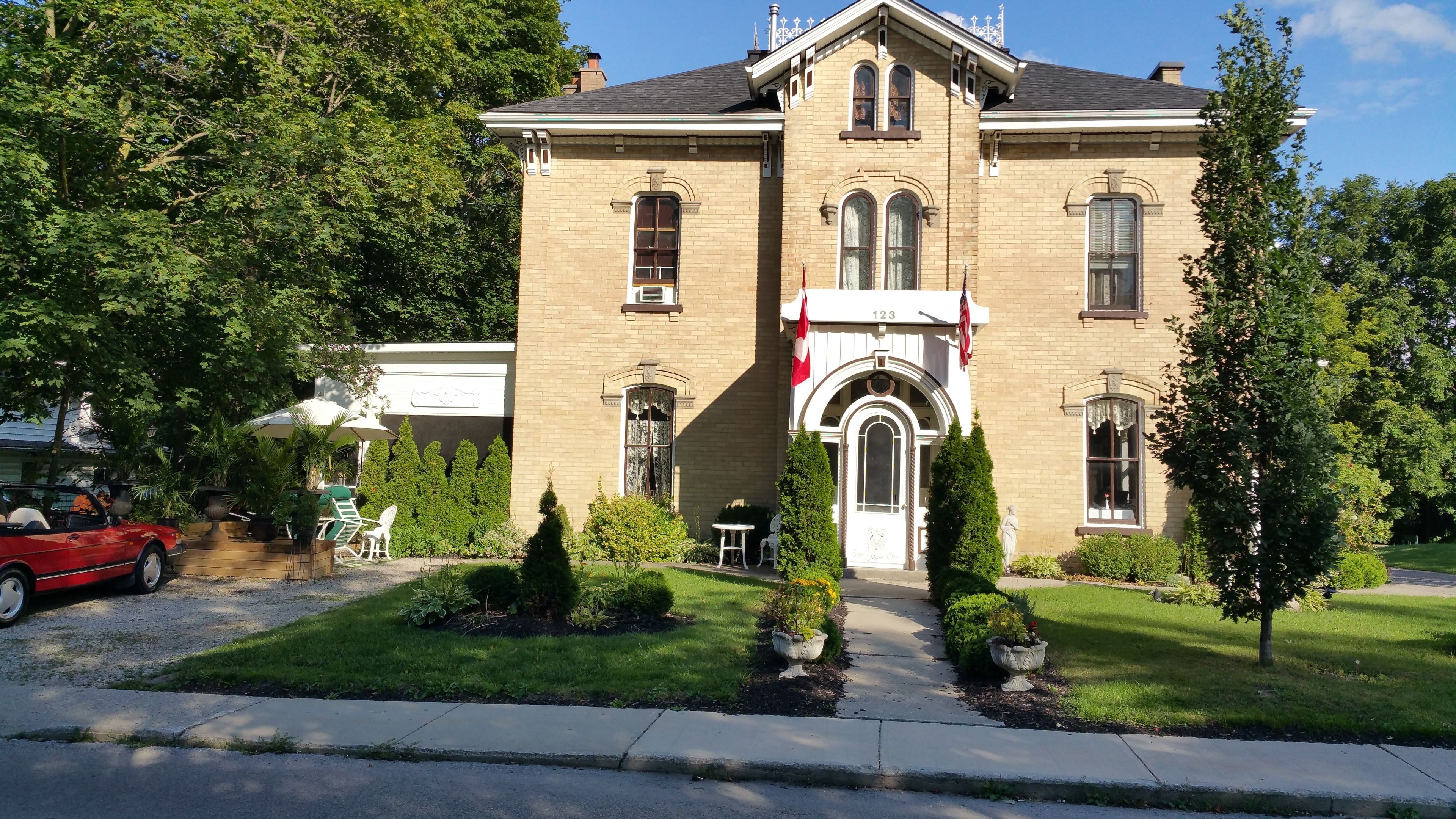 A two-story brick building with a central entrance, a flag, and a statue.