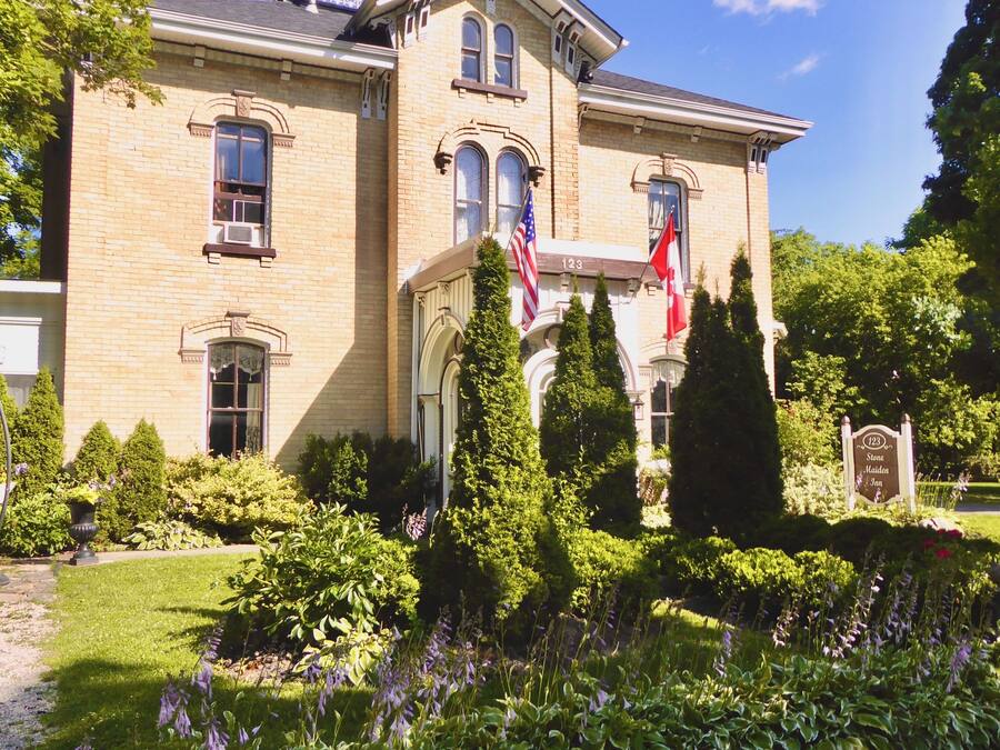 Een groot, historisch stenen gebouw met een opvallende Amerikaanse vlag en een Canadese vlag.