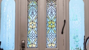 A door with stained glass windows, an exit sign, and a chandelier.