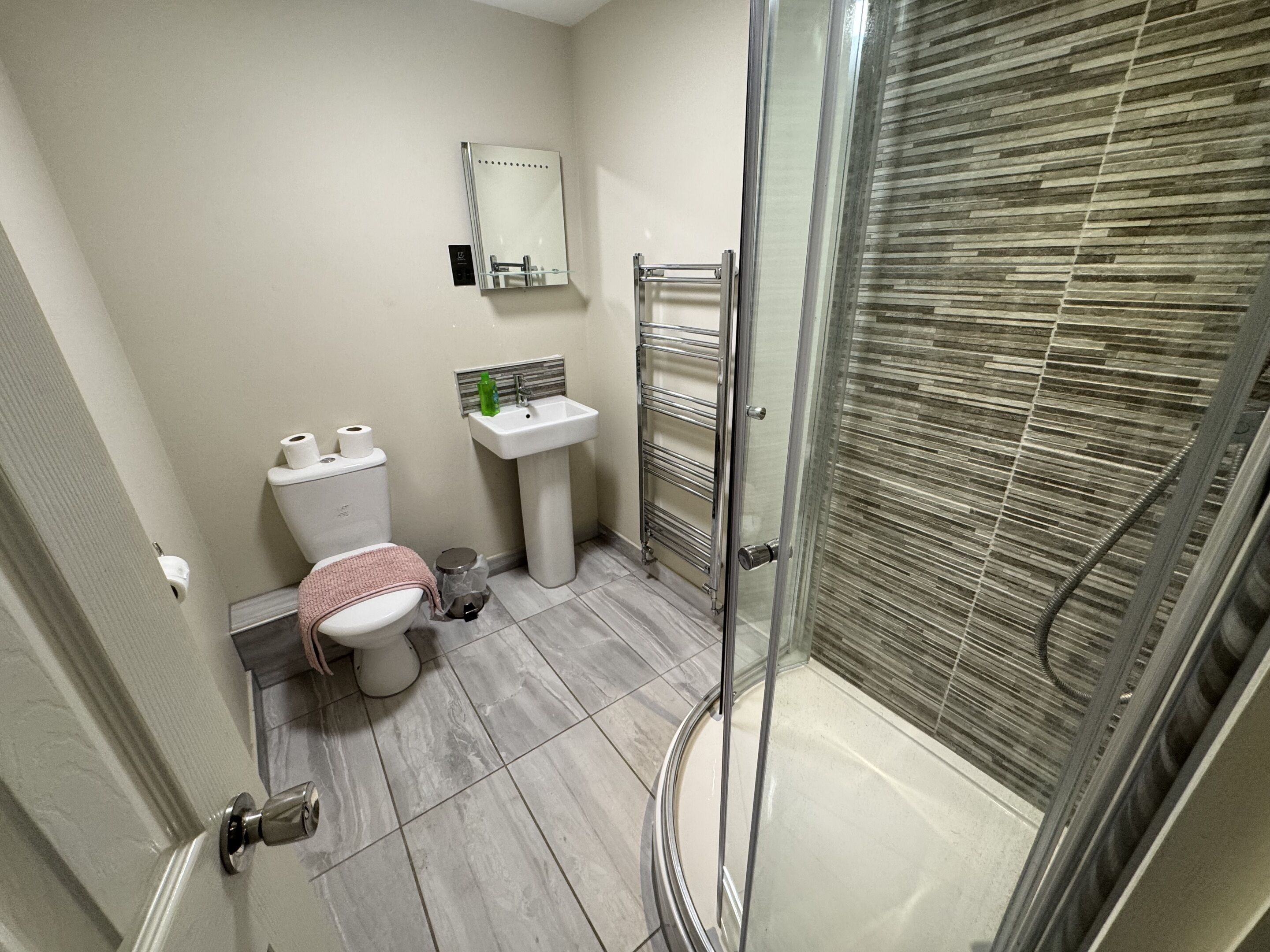 Une salle de bain équipée de toilettes, d’un lavabo et d’une douche à parois en verre.