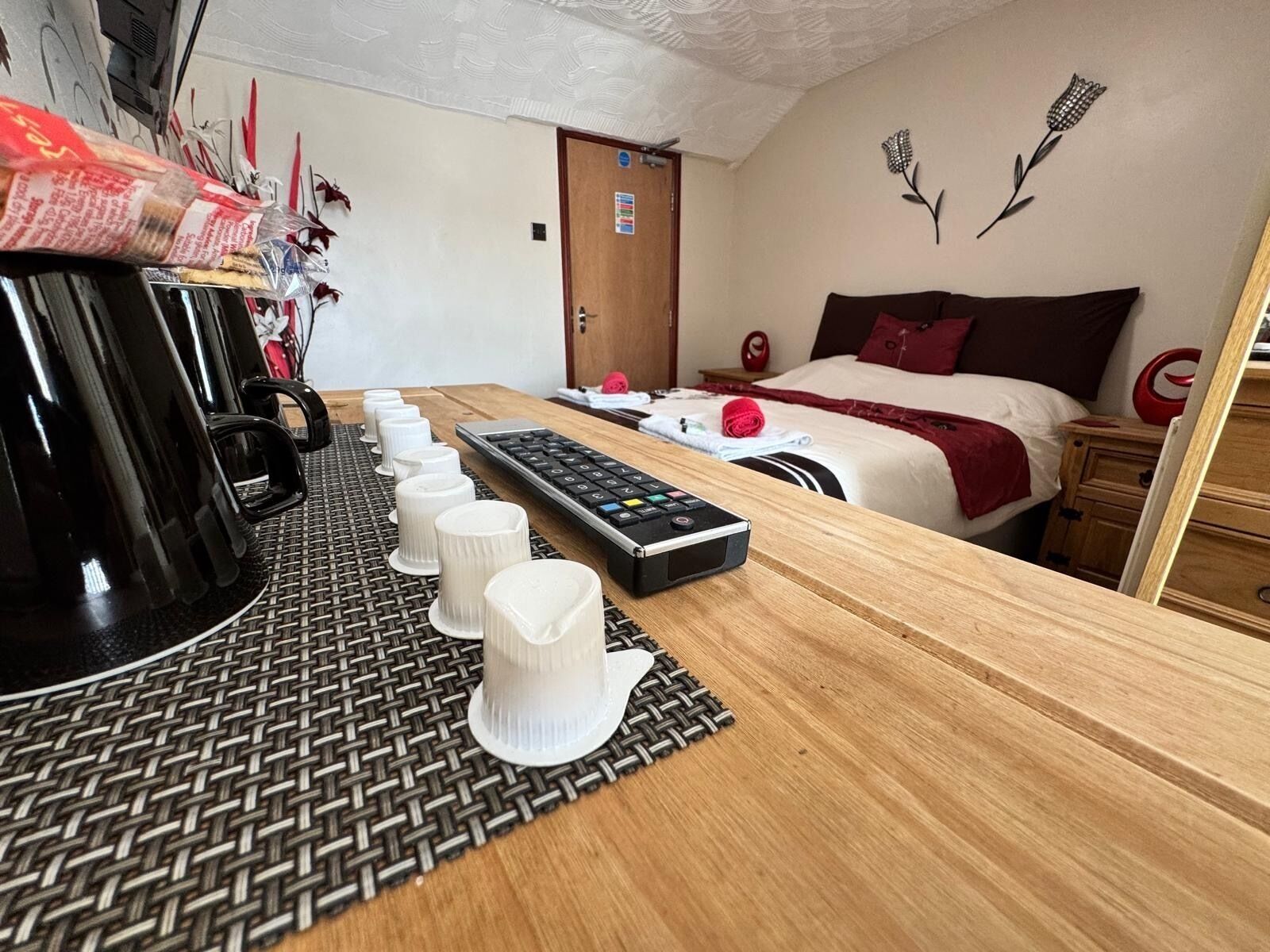 Une chambre d’hôtel avec un lit, un bureau doté d’un clavier, une machine à café et un mur décoré de motifs floraux.