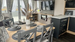 A modern dining area with a wooden table set for four, grey chairs, and a vase with dried plants. - The Kings Head inn (Skegness)