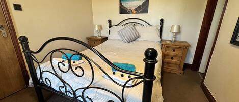 A bedroom with a four-poster bed, wooden nightstands, a night lamp, and a heart-shaped picture on the wall.
