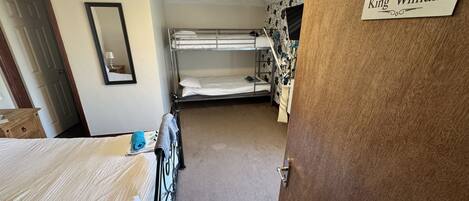 A room with bunk beds, a wooden door, a mirror, and a sign reading "King William".