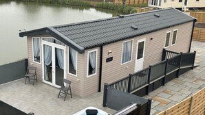 A small, single-story building with a covered patio area, a hot tub, and a view of a body of water. - The Kings Head inn (Skegness)