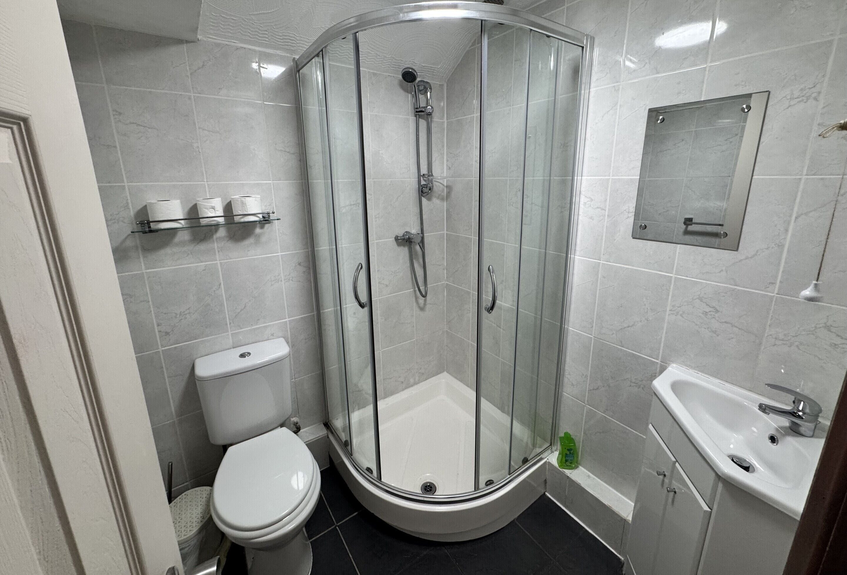 Une salle de bain moderne avec une douche à parois de verre, des toilettes et un lavabo.
