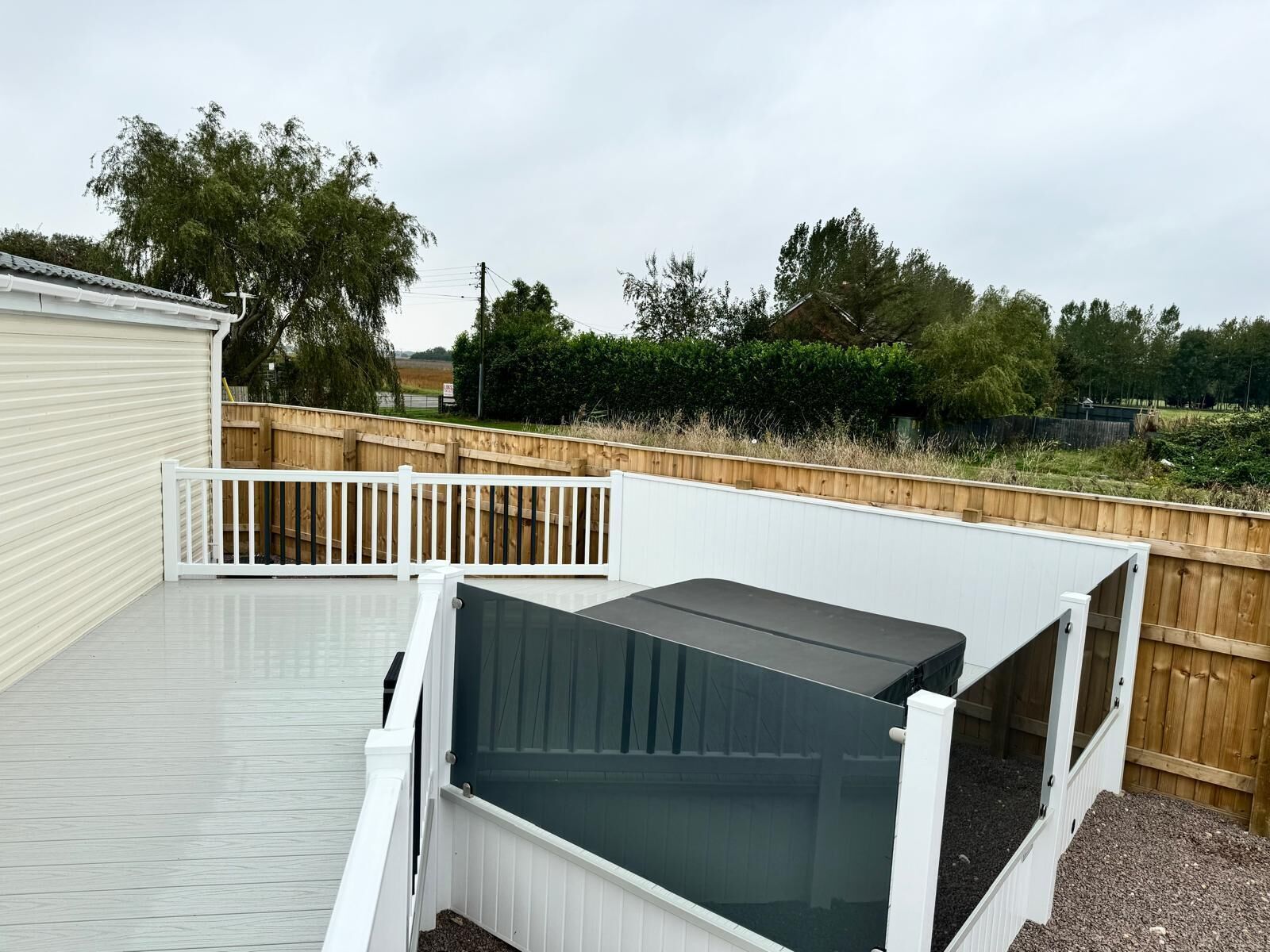 A fenced backyard with a raised platform and a covered area.