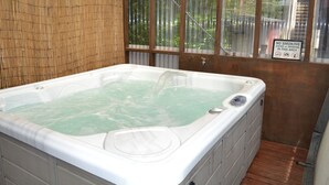 Un bain à remous avec un décor en bambou et un panneau indiquant « Il est interdit de fumer ».