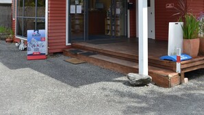 Un bâtiment rouge avec une entrée couverte, une enseigne et un pot de fleurs.