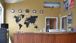 Un comptoir d’accueil orné d’une carte du monde et de plusieurs horloges indiquant l’heure à New York, Londres, Berlin et Tokyo.