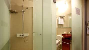 A bathroom with a glass shower enclosure, a white toilet, and a red sink.