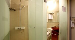 A bathroom with a glass shower enclosure, a white toilet, and a red sink.