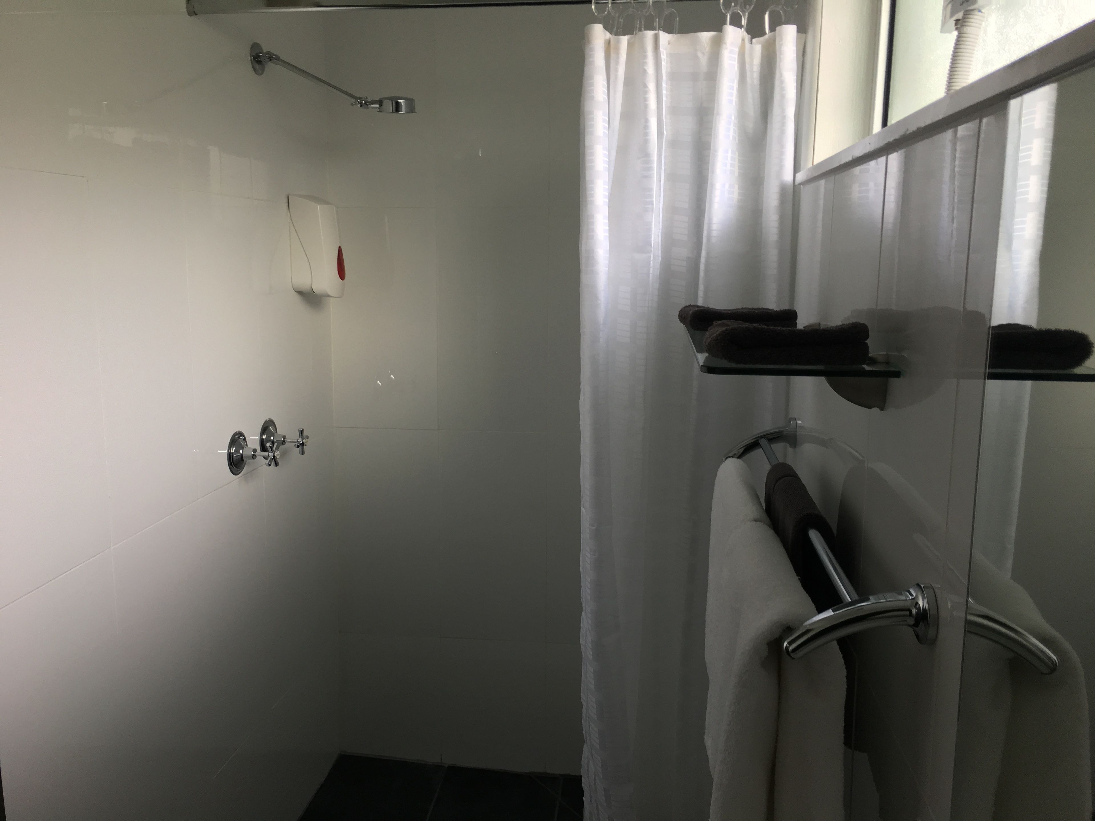 Un baño moderno con cabina de ducha de vidrio, ducha de mano y toallero con toallas.