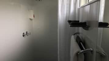 Un baño moderno con cabina de ducha de vidrio, ducha de mano y toallero con toallas.
