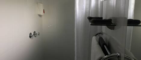 Un baño moderno con cabina de ducha de vidrio, ducha de mano y toallero con toallas.