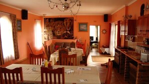 Un comedor con un cuadro grande de animales en la pared, sillas de madera y una araña.