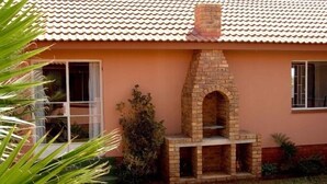 Una casa con chimenea de ladrillo, una ventana y un pequeño porche.
