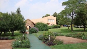 Un camino que lleva a un edificio con un arco de piedra, rodeado de follaje y árboles.