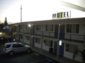 A motel with a signboard, a parking lot, and a building with multiple floors.