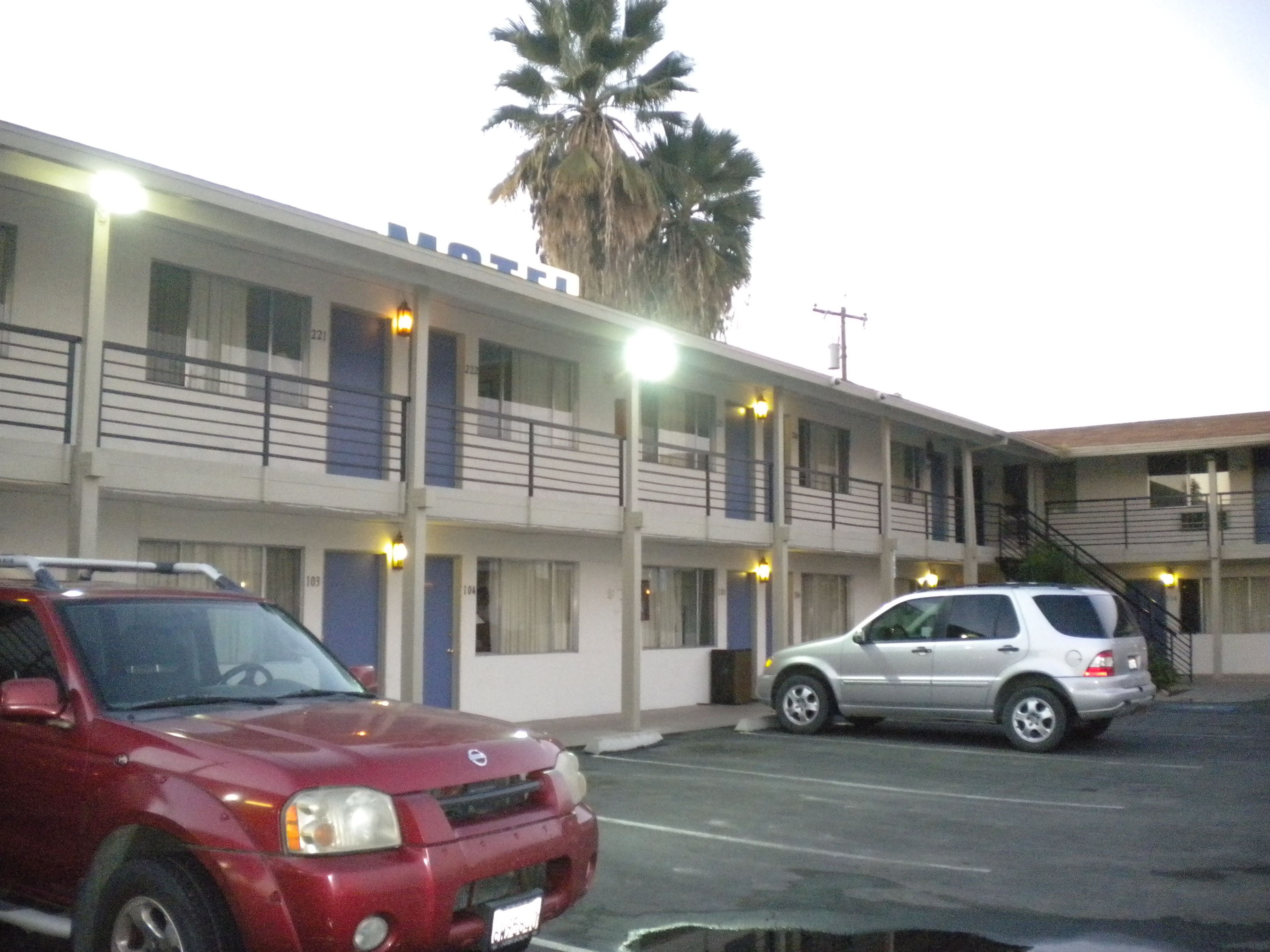 A motel with a two-story structure, multiple rooms, and a parking area with two cars.