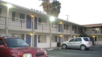 A motel with a two-story structure, multiple rooms, and a parking area with two cars.