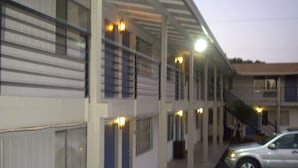 A motel with multiple floors, exterior lighting, and a parking area with a car. - Wasco Inn Motel (Wasco)