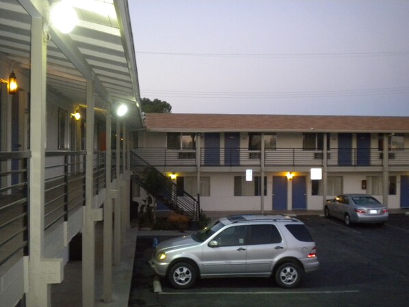 A motel with a two-story structure, a covered parking area, and a staircase leading to the upper level.