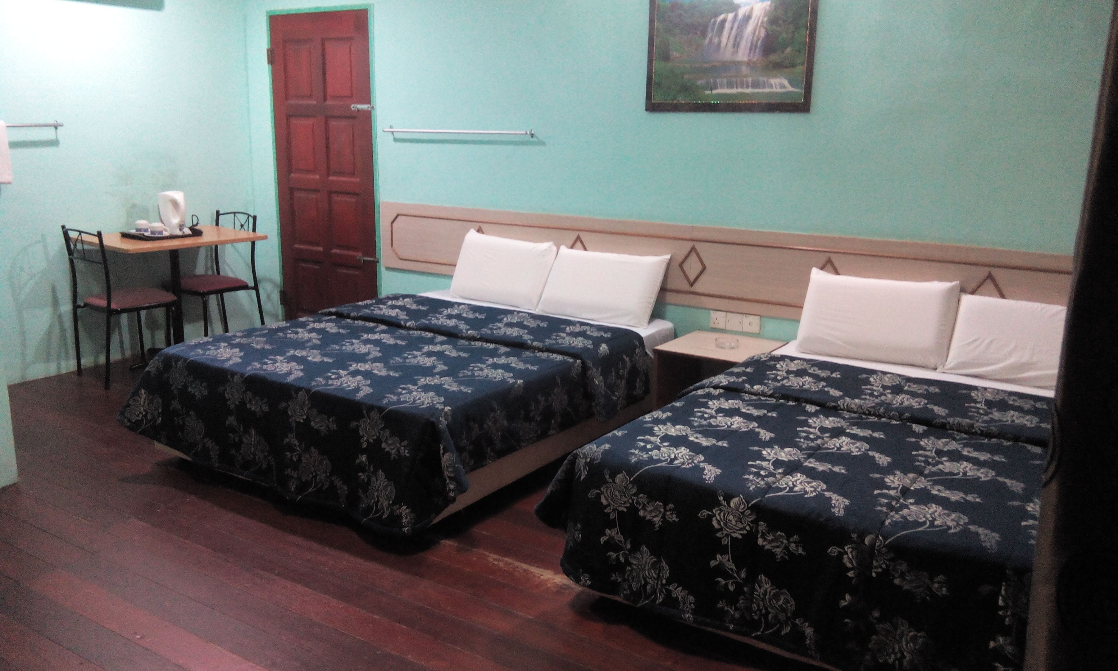 A room with two beds, a desk, a chair, and a door.