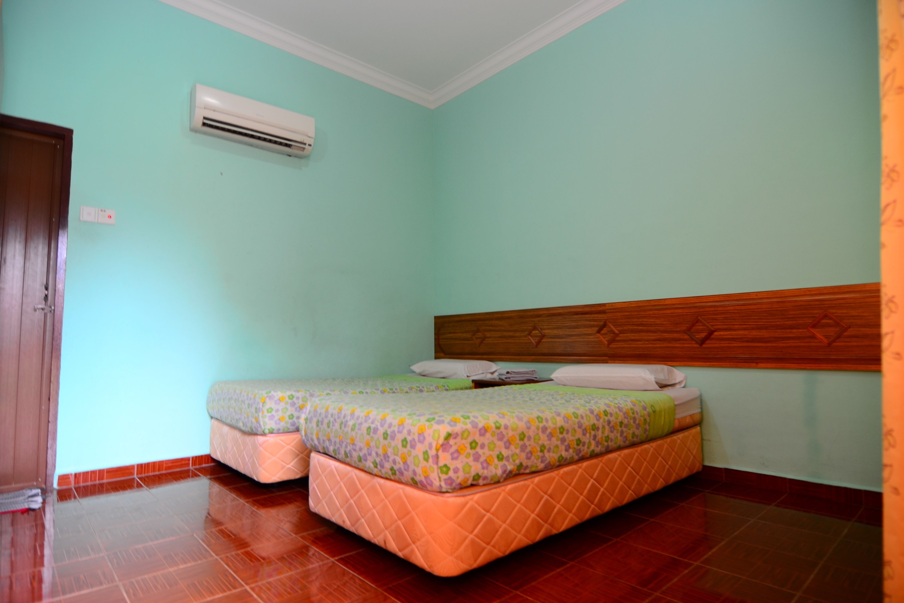 Een kamer met een bed, een airconditioning en een houten deur.
