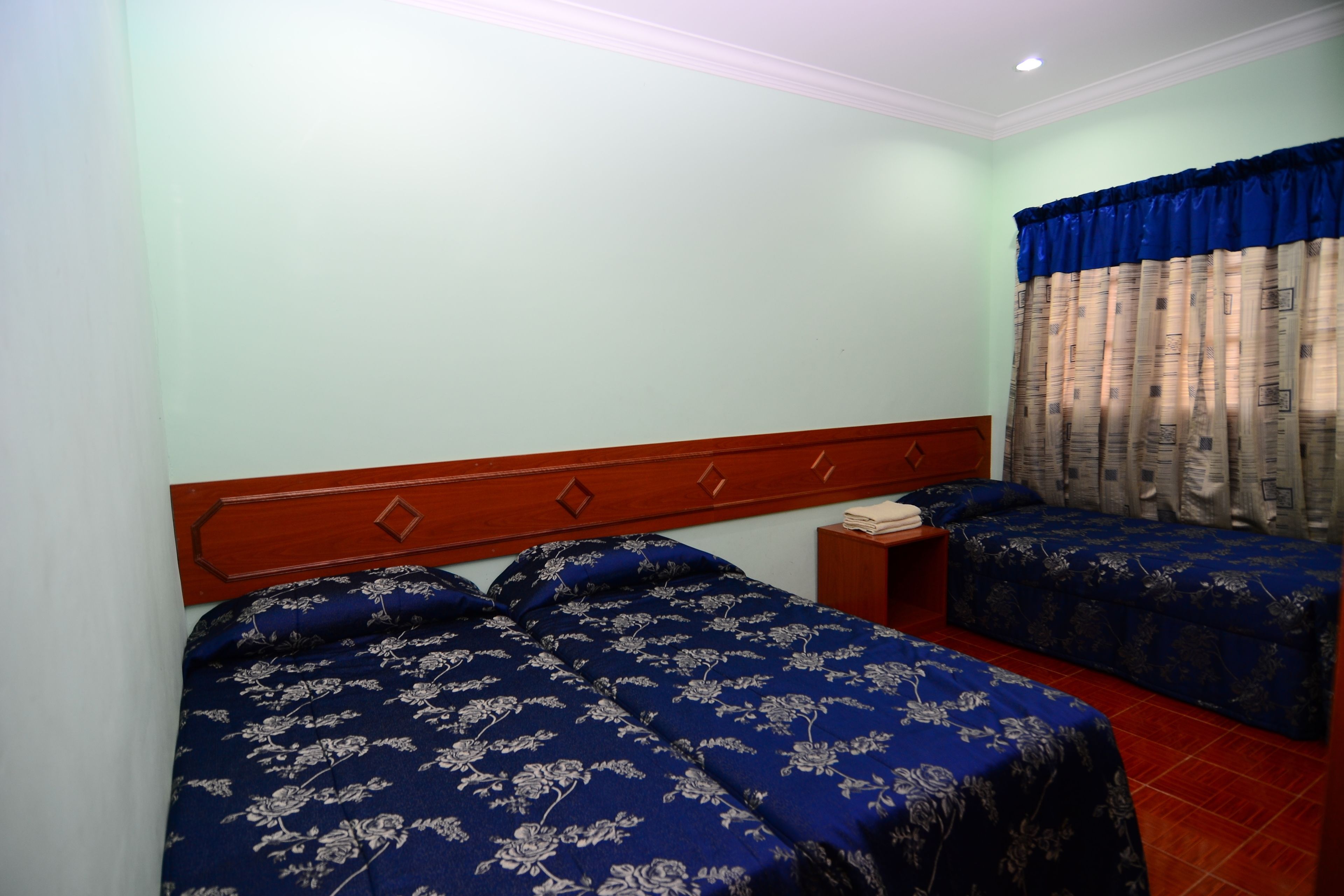 A bedroom with two beds, a wooden headboard, and a nightstand.