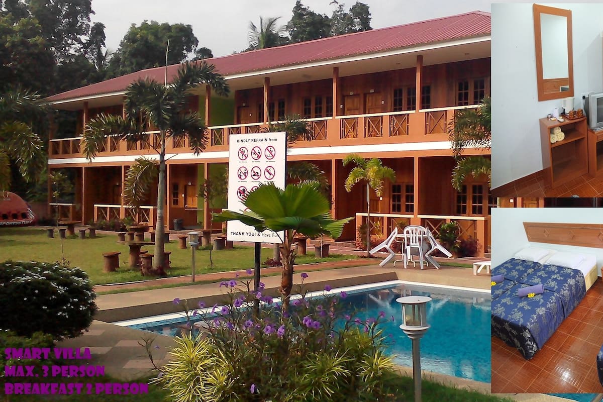 A two-story building with a pool, outdoor seating, and a sign indicating a maximum of 3 persons for breakfast.