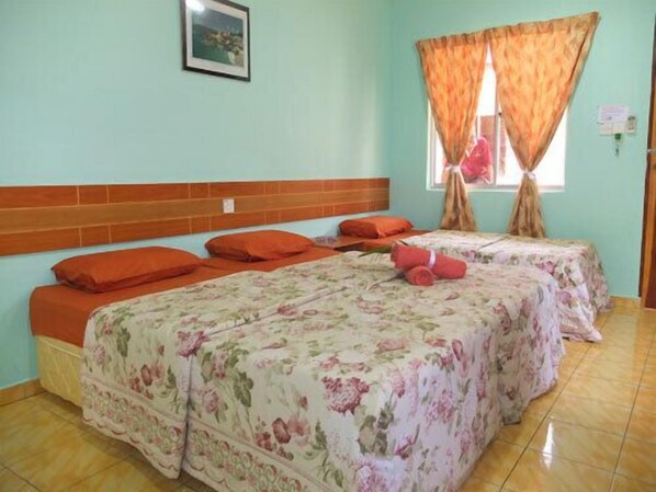 A room with two beds, each with floral bedding and orange pillows.
