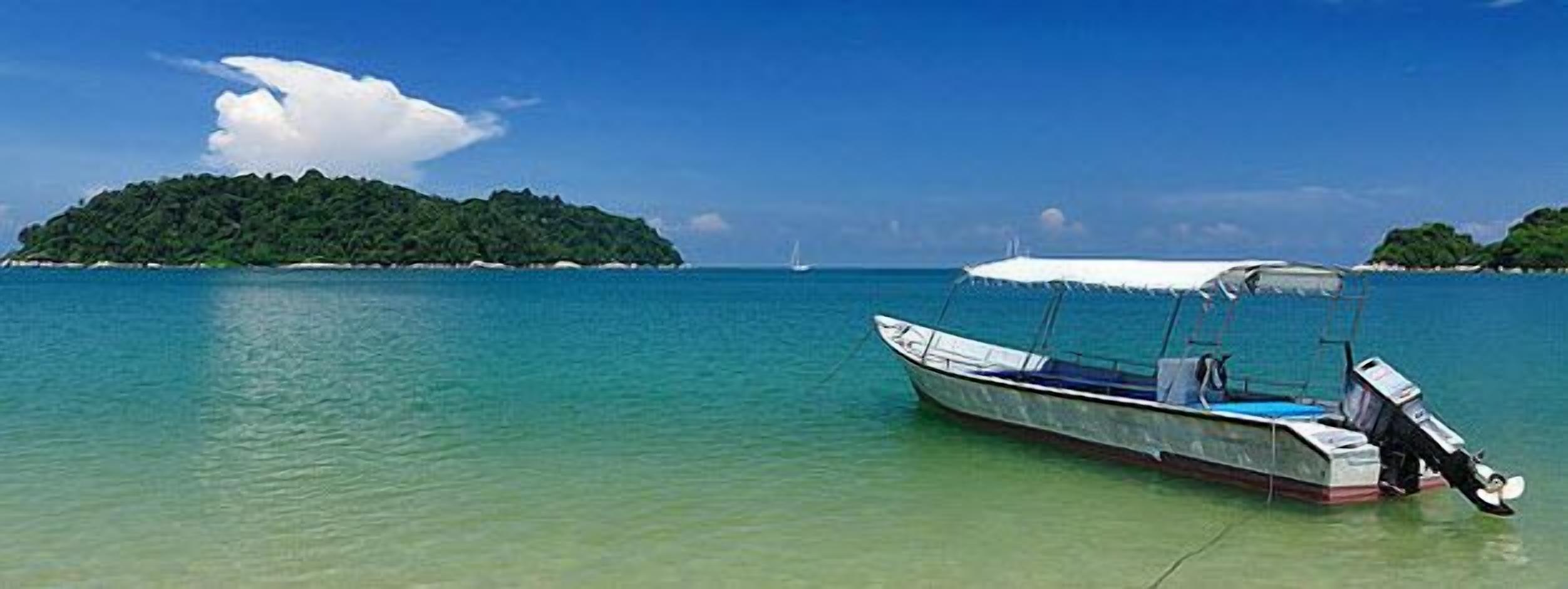 A boat anchored near a small island with clear turquoise water.
