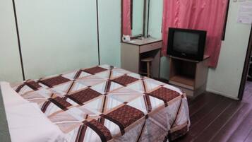 A bedroom with a bed, a desk, a television, and a mirror.