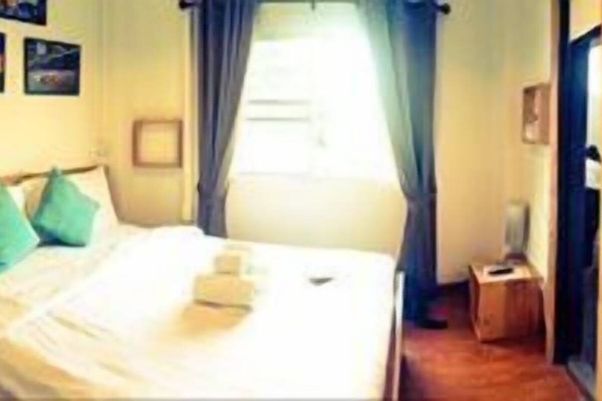 Un dormitorio con cama, armario de madera, mesita de noche y ventana con cortinas.