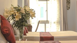 A room with a bed, a vase with flowers, a window with curtains, and a wall decoration. - Sao Nam Hotel - Bui Vien Walking Street (Ho Chi Minh City)