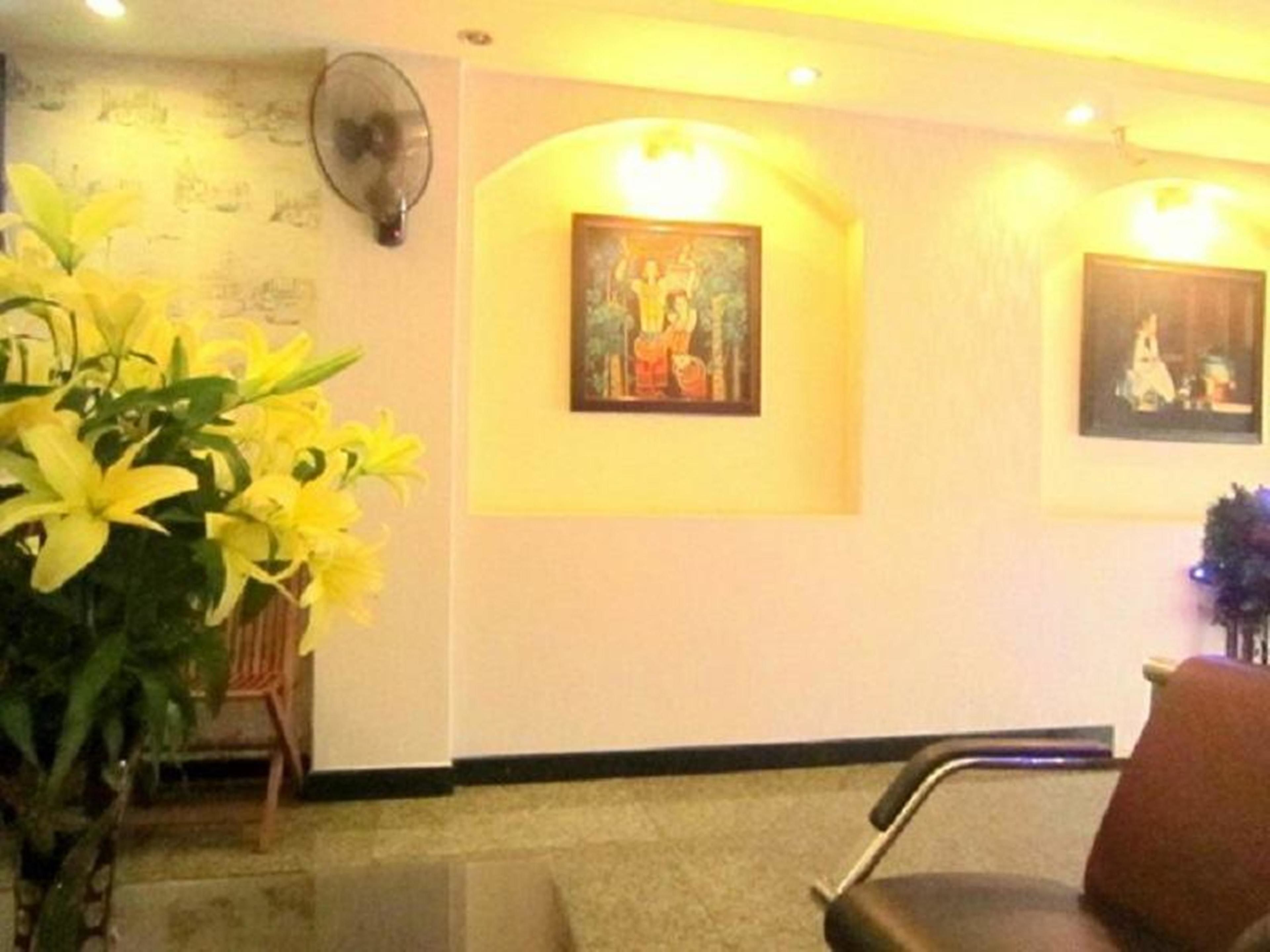 A reception area with a chair, a fan, and two framed paintings on the wall.
