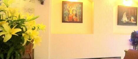 A reception area with a chair, a fan, and two framed paintings on the wall.