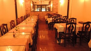 A long dining room with tables and chairs, a brick wall, and a chandelier. - Sao Nam Hotel - Bui Vien Walking Street (Ho Chi Minh City)
