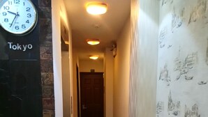 A hallway with a clock displaying the time, a red mat on the floor, and a wall with a pattern of buildings. - Sao Nam Hotel - Bui Vien Walking Street (Ho Chi Minh City)