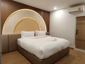 Ein modernes Schlafzimmer mit Bett, integriertem Kopfteil und Wand-Klimaanlage.