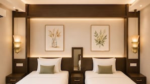 Habitación de hotel con dos camas, un espejo grande, una obra de arte en la pared y lámparas de noche.