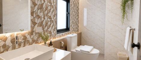 Un baño moderno con un lavamanos grande blanco, un inodoro y una ventana.