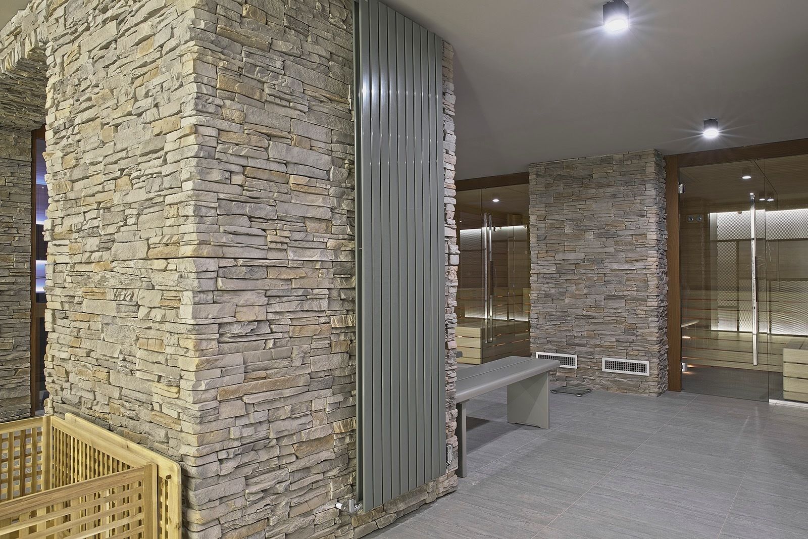 A modern interior with stone walls, a bench, and a glass partition.