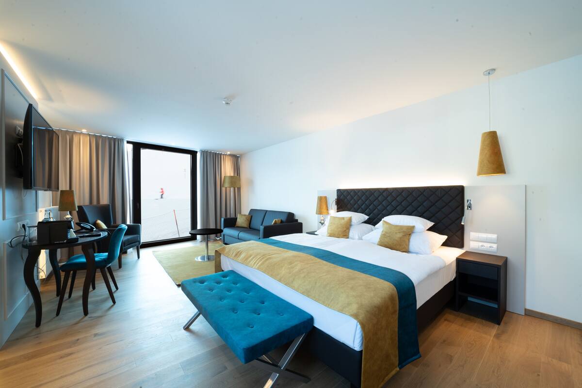 Una habitación de hotel moderna con una cama grande, un escritorio, una silla y un banco.