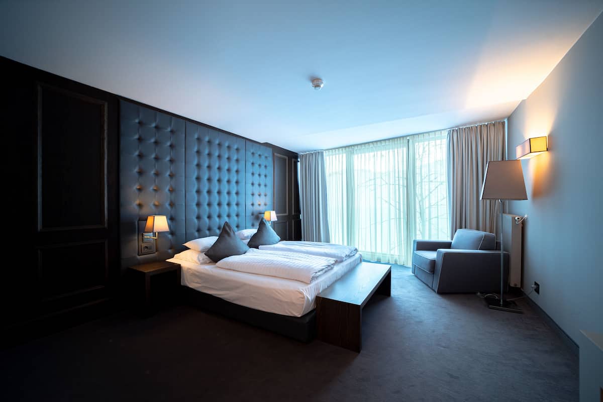 Habitación de hotel moderna con una cama grande, un área de descanso y vistas al exterior.